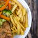 Delicious chicken dinner with broccoli, carrots, and fries on a plate.